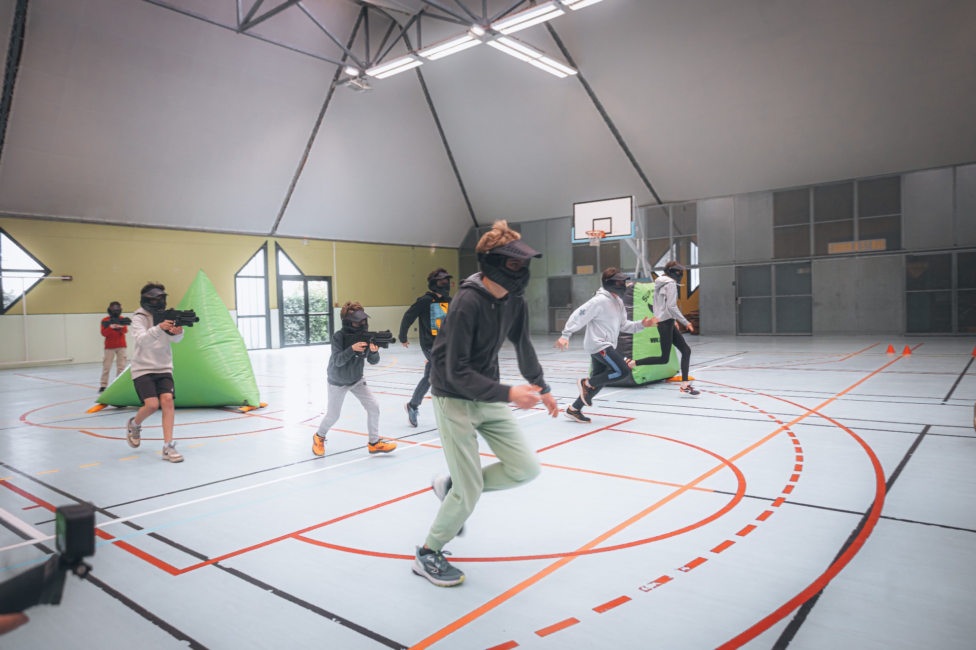 Enfants et ados jouant au laser game en salle de sport avec obstacles gonflables